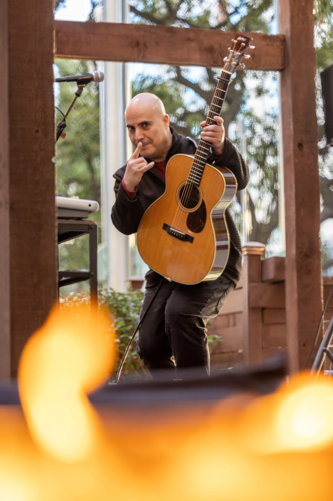 Live musician framed through firepit flame after dark