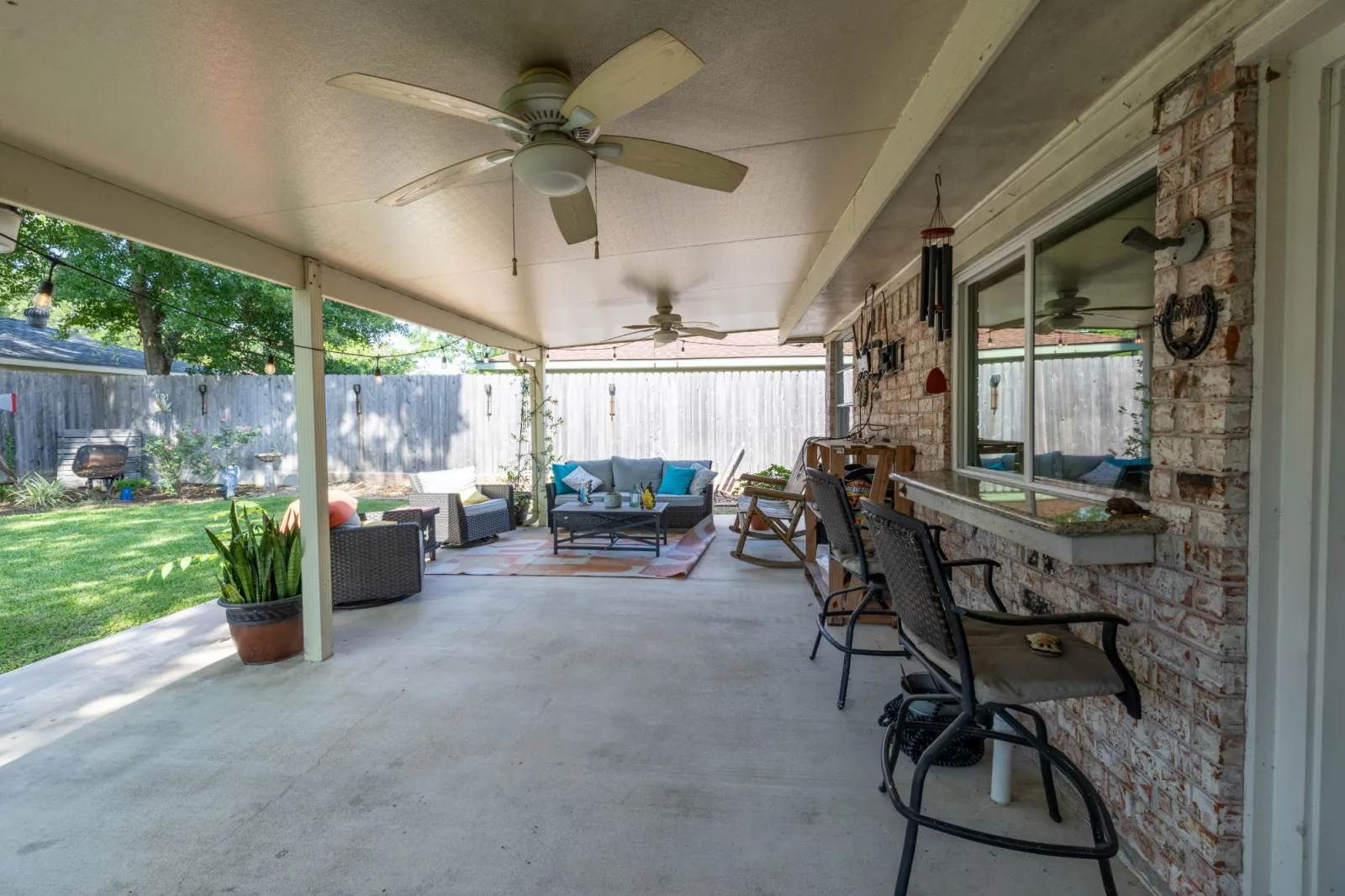 Covered patio living space at a Meadows Place listing, shot from under the roofline